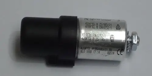 Kondensator mit schwarzem Kunststoffgehäuse und Metallzylinder, beschriftet mit technischen Angaben. Teil eines Heizsystems von Daikin, möglicherweise für ROTEX A1 BO Modelle.
